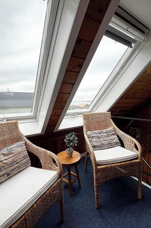 A room with two wicker chairs, a small round table with a plant, and a view through skylights. - Sleep under the stars near Brunsnæs Beach (Broager)