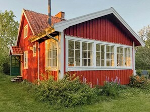 Ein rotes Holzhaus mit großem Fenster, Schornstein und grüner Tür.