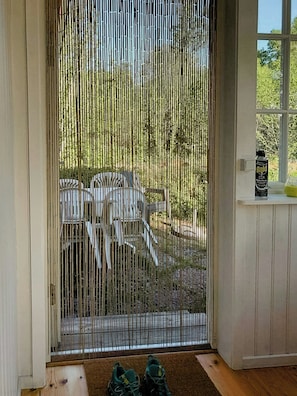 Ein Zimmer mit einer Schiebetür, die auf einen Außenbereich mit Stühlen und einem Tisch führt.