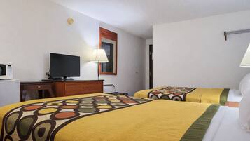 A hotel room with two beds, a desk with a television, a microwave, and a lamp.