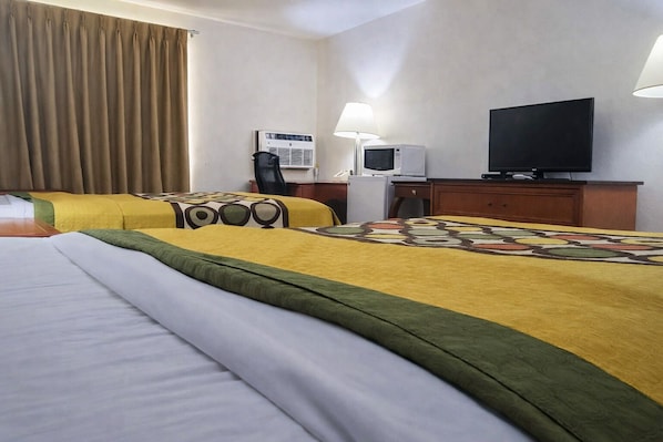 Een hotelkamer met twee bedden, een televisie, een bureau met lamp en een magnetron.