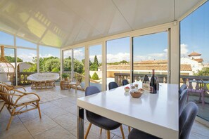 Un espace extérieur abrité, aménagé pour les repas, avec une table, des chaises et une vue sur le paysage urbain.