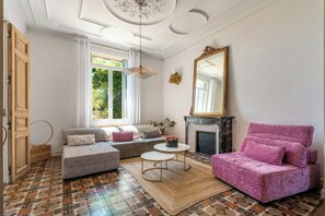 Sala de estar com sofá, banquinho, mesa de centro, lareira e um espelho grande.