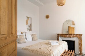 Une chambre à coucher avec un lit, un miroir, une cheminée et un banc en bois.