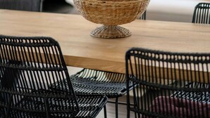 A dining area with a wooden table, black chairs, and a woven bowl centerpiece. - House with infinity pool near Aix (Aix-en-Provence)