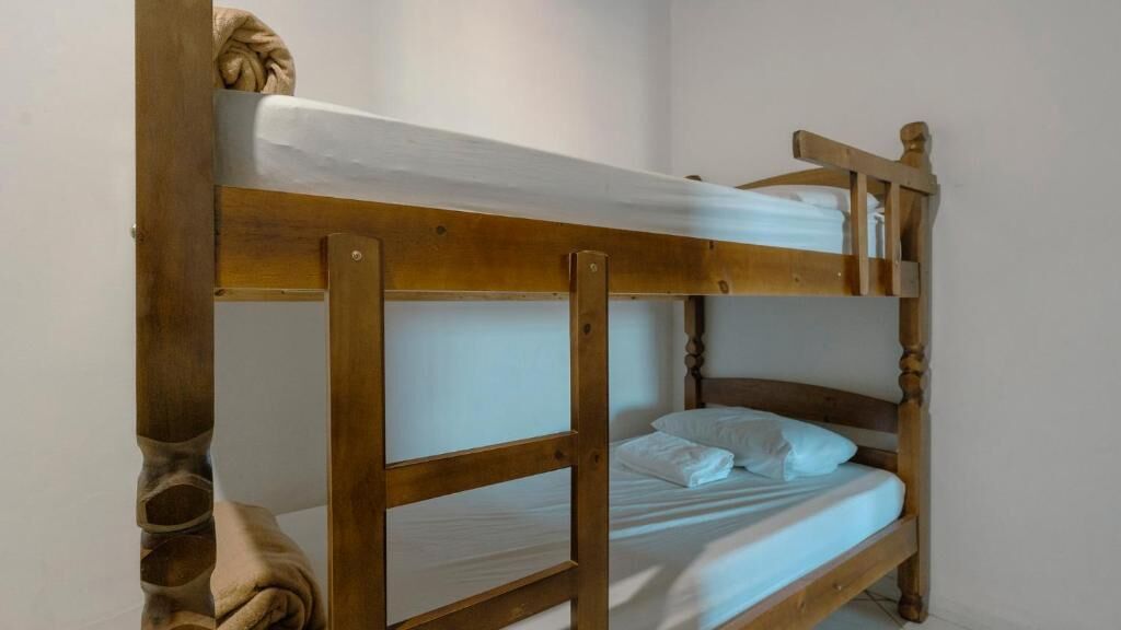 A bunk bed with a wooden frame and white bedding.