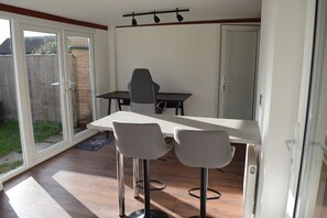 A dining area with a table and two chairs, a sliding glass door, and a white wall.