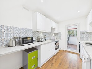 A modern kitchen with white cabinets, a microwave, toaster, and a green cabinet.