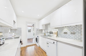 A modern kitchen with white cabinetry, a washing machine, and a dishwasher.