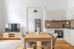 A modern kitchen with white cabinets, a wooden countertop, a built-in oven, and a microwave. - Blueground | Alsergrund, view, nr Votivkirche (Vienna)