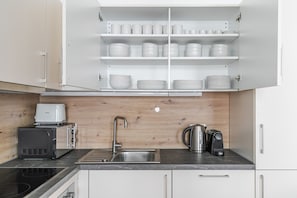 A modern kitchen with white cabinets, a stainless steel sink, a coffee maker, and a toaster. - Blueground | Alsergrund, view, nr Votivkirche (Vienna)