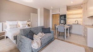 A modern, compact living space with a sofa, a dining table, and a kitchenette. - Nowoczesne Studio Tranquilo Centrum Balkon (Bydgoszcz)