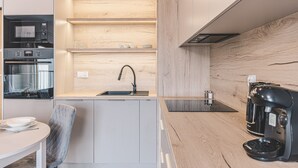 A modern kitchen with built-in appliances, a wooden backsplash, and a coffee maker. - Nowoczesne Studio Tranquilo Centrum Balkon (Bydgoszcz)