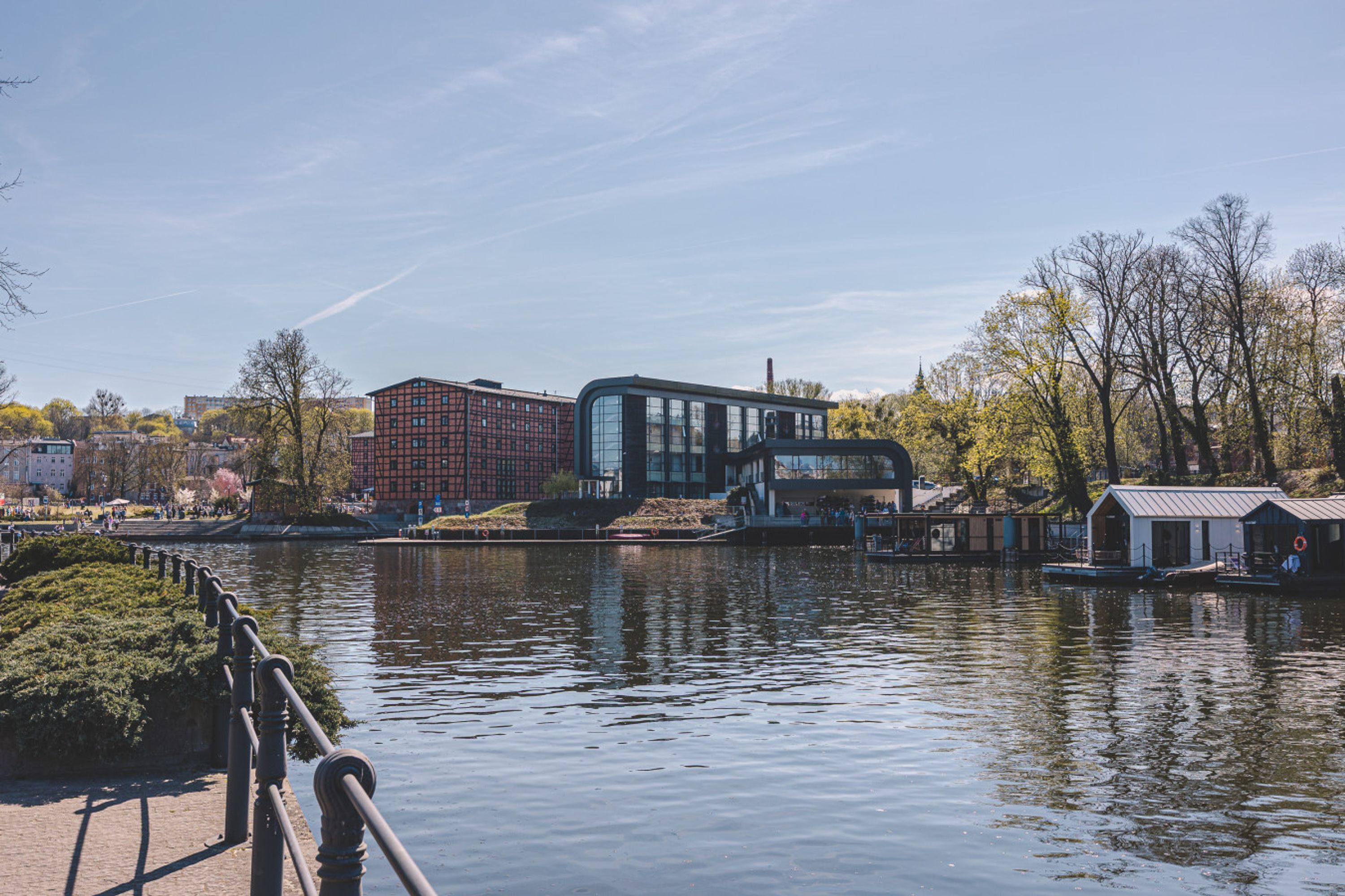 A riverside view with a modern building, a bridge, and a small dock.