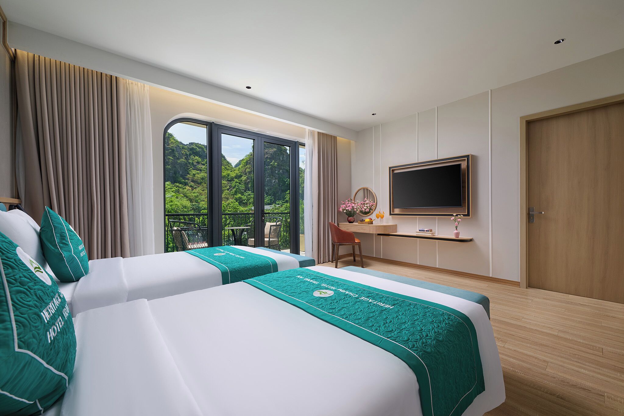 Hotelkamer met twee bedden, een televisie, bureau en groot raam met uitzicht op groen.