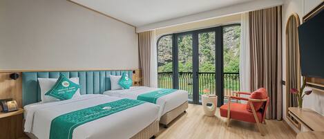 A hotel room with two beds, a red chair, a small table, and a balcony with curtains.