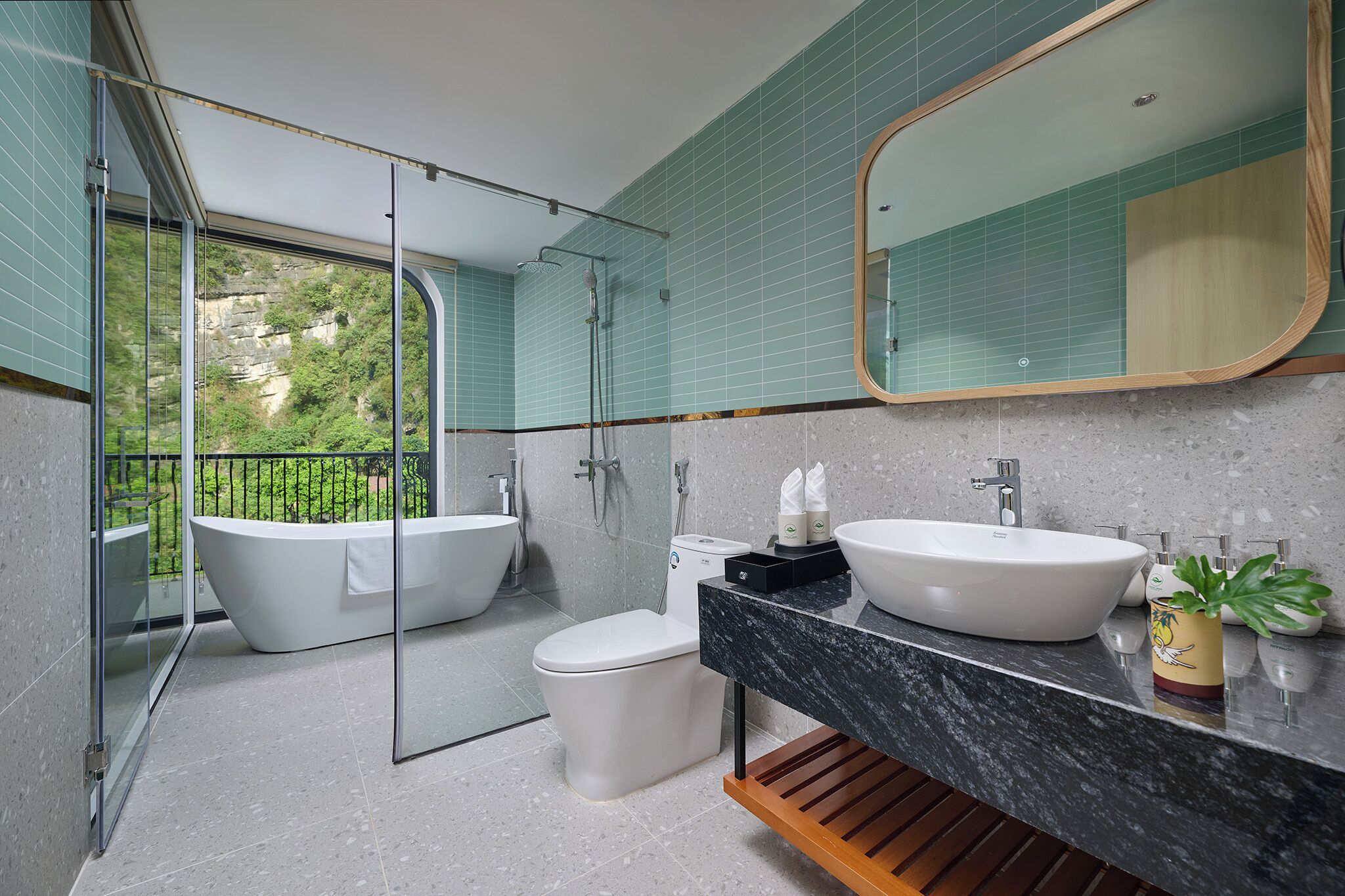Un baño moderno con bañera, inodoro y lavamanos, que cuenta con una ducha con cerramiento de vidrio y vistas al exterior.