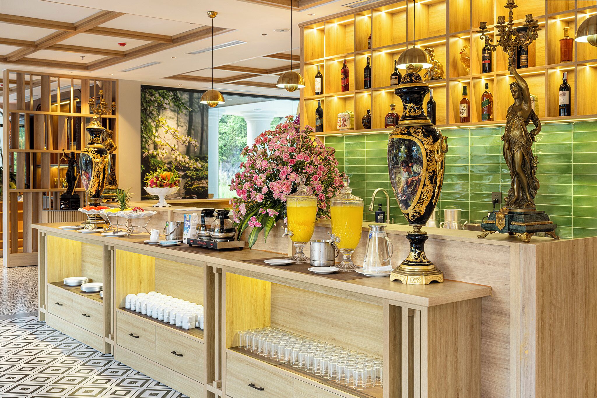 A hotel lobby with a reception desk, a green tiled wall, and a statue.