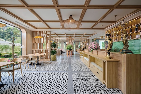Un intérieur moderne avec un plafond en bois, un sol à motifs, un coin bar agrémenté d’objets décoratifs et une vue dégagée sur l’extérieur grâce à une grande fenêtre.