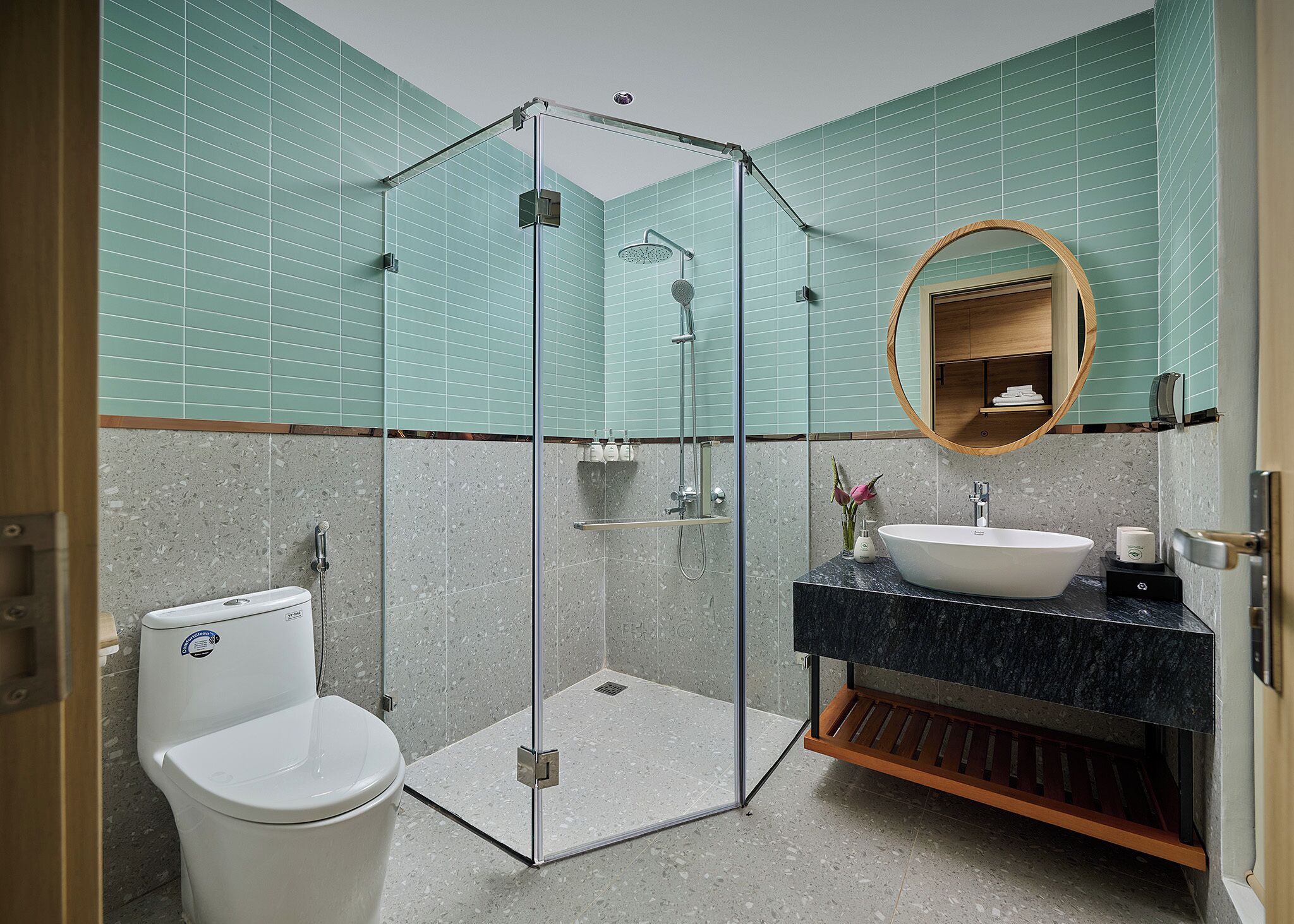 Une salle de bain moderne dotée d’une douche à parois de verre, de toilettes blanches, d’un lavabo avec un plan de travail en marbre et d’un miroir avec un cadre en bois.