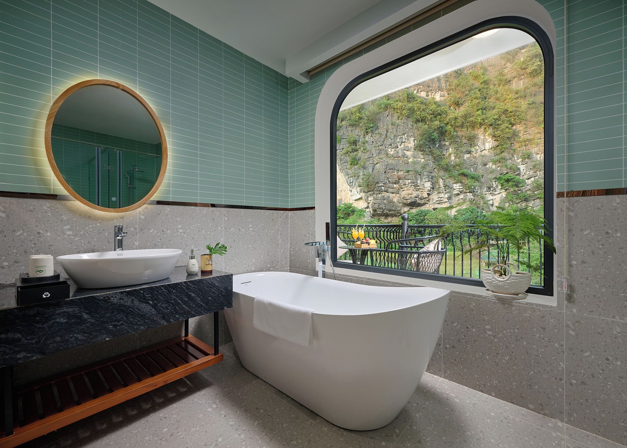 A bathroom with a freestanding bathtub, two sinks, a large mirror, and a view of a balcony with plants.