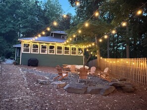 Ein rustikales Blockhaus mit Veranda, Sitzgelegenheiten im Freien und Lichterketten.