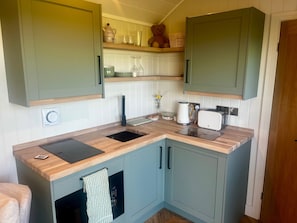 A compact kitchen with a sink, a toaster, and a kettle. There are cabinets and a countertop.