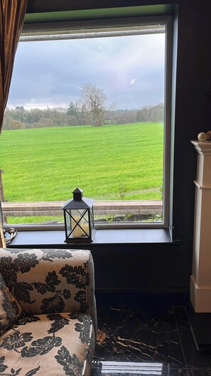 Ein Zimmer mit einem großen Fenster, einem schwarz-weißen Sofa mit Muster und einer kleinen schwarzen Laterne auf der Fensterbank.