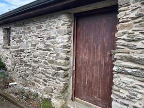 A stone building with a wooden door and a small window.