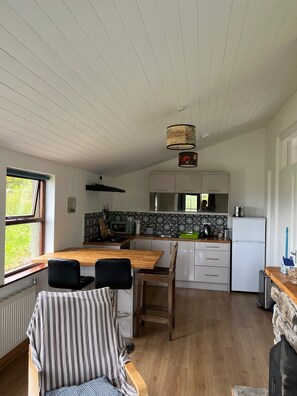 A modern kitchen with a wooden table, chairs, a microwave, and a refrigerator.