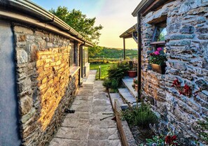 A stone pathway leading to a building with a wooden porch and flower pots.