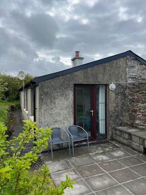 A small building with a stone exterior, a glass door with a red frame, and a satellite dish.