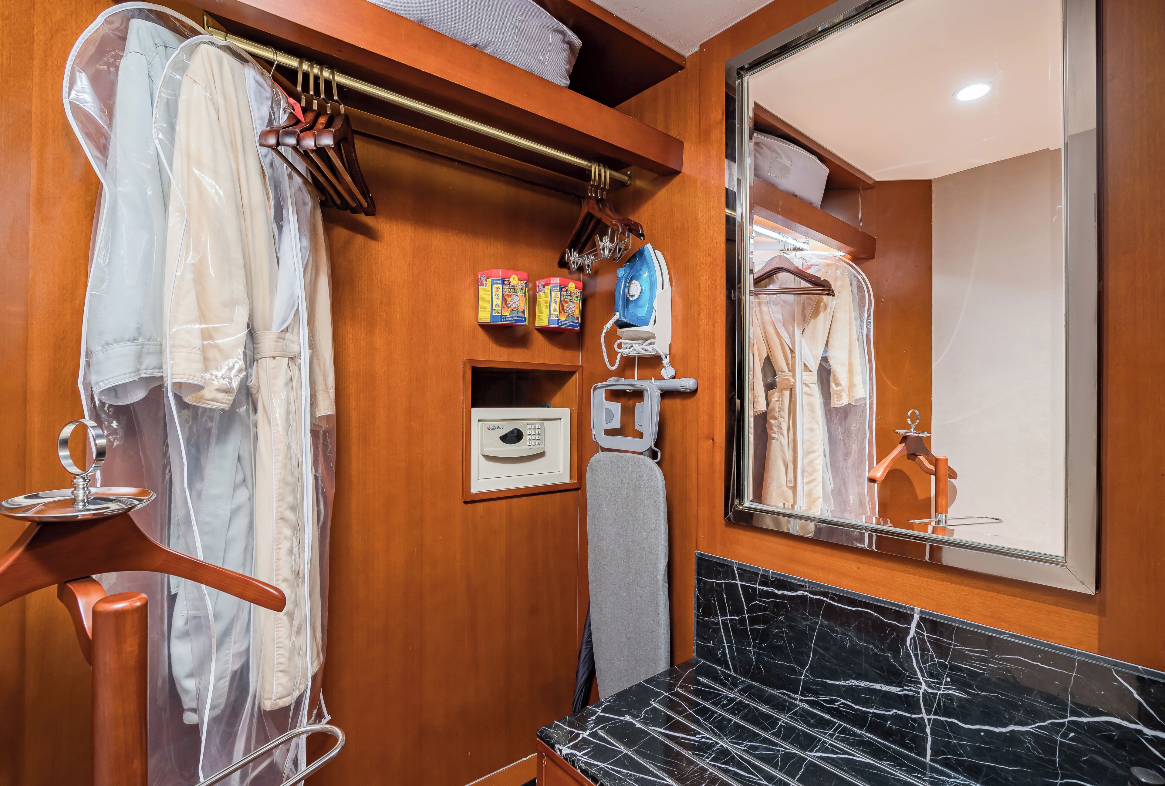 A bathroom with a wooden vanity, a mirror, a black marble sink, and a towel rack with hanging towels.