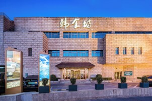 A hotel with a brick facade, a sign with Chinese characters, and a well-lit entrance.