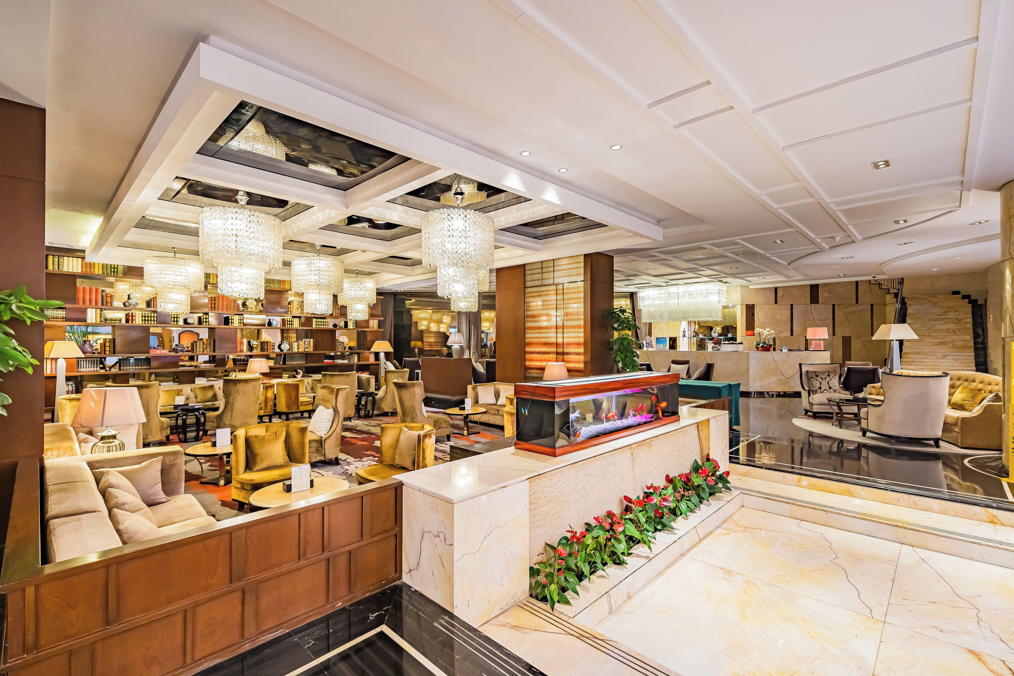 A spacious lobby with a reception desk, seating area, and a large chandelier.
