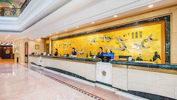 A hotel reception area with a marble floor, a reception desk, and a large wall mural.