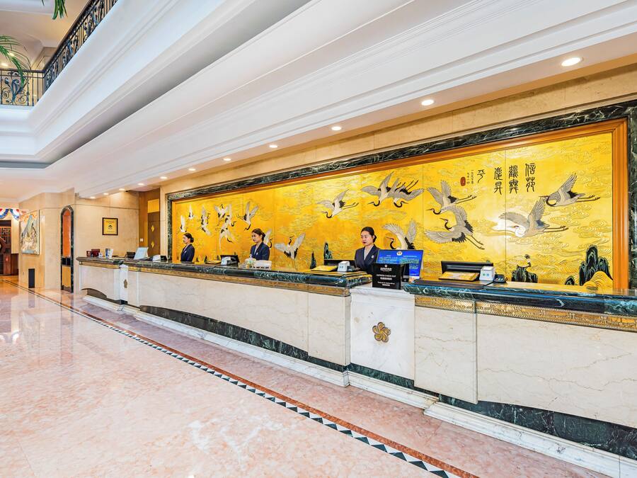 A hotel reception area with a marble floor, a reception desk, and a large wall mural.