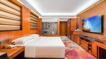 A hotel room with a bed, bedside table, TV, and a view of the bathroom.