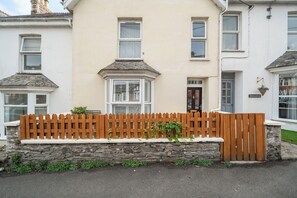 A residential building with a stone wall, a wooden fence, and a clear sky. - 1 Bed - Sleeps 4 - Parking - Pets - Town Centre (Wadebridge)