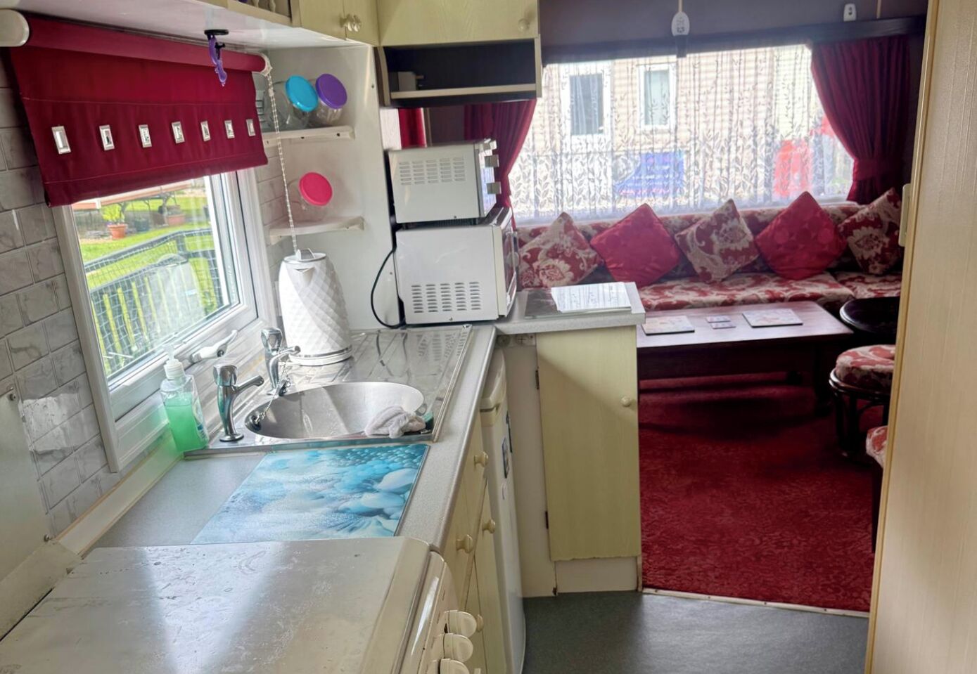 A compact kitchen with a sink, a microwave, and a window with a view of a garden.