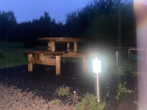 Una mesa de picnic de madera con banco, rodeada de un jardín.