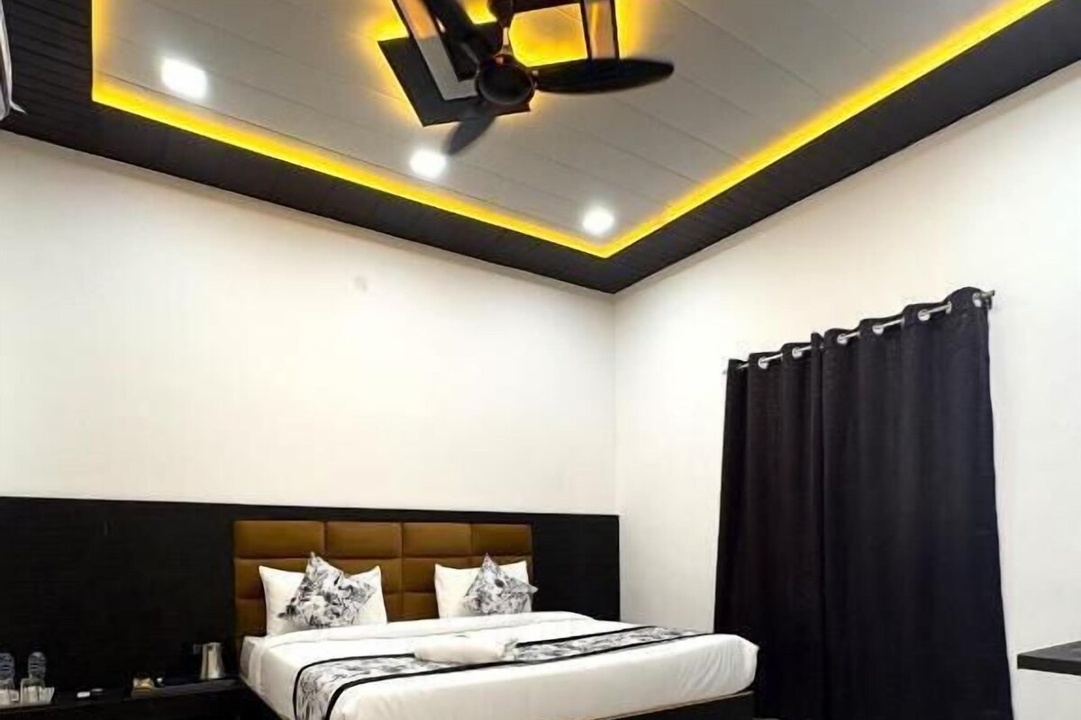 Een moderne slaapkamer met een groot bed, een plafondventilator en een zwart gordijn.