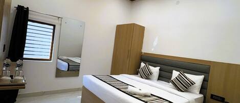 A modern bedroom with a large bed, a ceiling fan, and a wooden wardrobe.