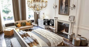 Ein Schlafzimmer mit einem großen Bett, einer Couch, einem Kamin und einem Chandelier.
