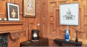 Ein Zimmer mit Holzwänden, einem Kamin, einem Tisch mit einer Vase und gerahmten Kunstwerken.