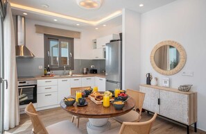 Eine moderne Küche mit weißen Schränken, einem Edelstahl-Kühlschrank und einem Essbereich mit einem Holztisch, gedeckt für das Frühstück.