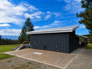 A modern building with a dark exterior, a flat roof, and a small porch area.