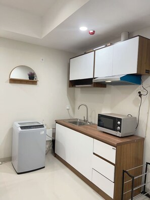 A compact kitchenette with a microwave, sink, and a small refrigerator.