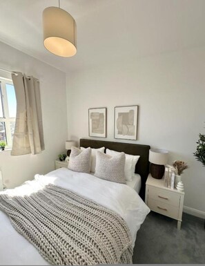 A bedroom with a bed, bedside tables, a hanging light, and two wall-mounted pictures. - Modern Elegant 2-bedroom at Devonshire Point Worsley (Moffat)