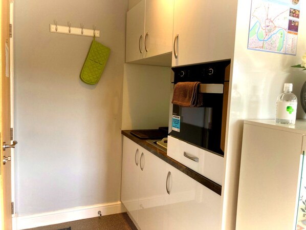 Eine Küche mit weißen Schränken, einem schwarzen Backofen, einem grünen Handtuch und einer Karte an der Wand.